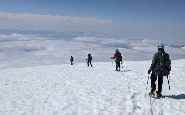 a group of students on a mountaineering course traverse a snowy mountainous landscape